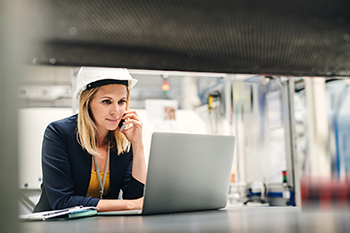 image of woman in hardhat using laptop